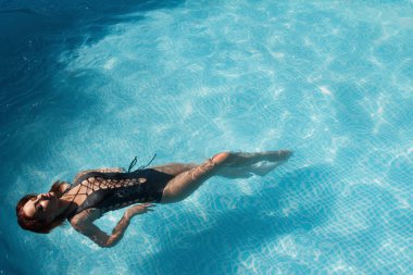 Şık bikinili seksi bir kızın moda fotoğrafı. Yüzme havuzunda güneşleniyor.