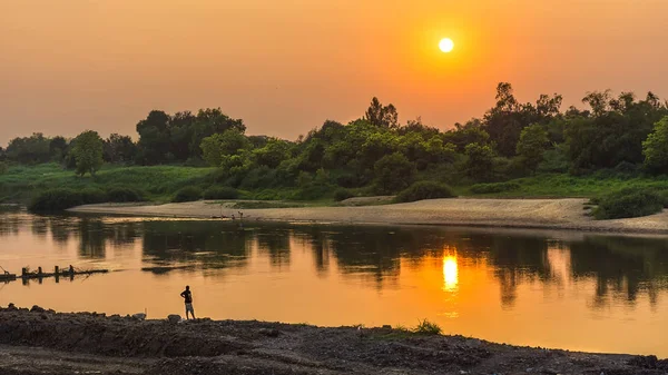 Yalnız insanlar yalnız nehirde gün batımını izlemek. — Stok fotoğraf