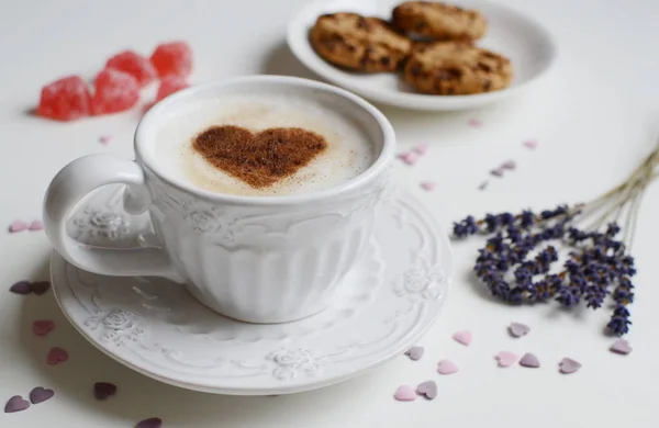 Cappuccino with heart pattern of cinnamon and flowers composition — Stock Photo, Image