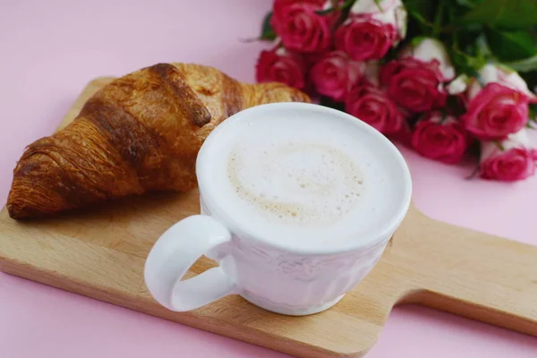 Чашка капучино и вкусный круассан с розовыми розами — стоковое фото