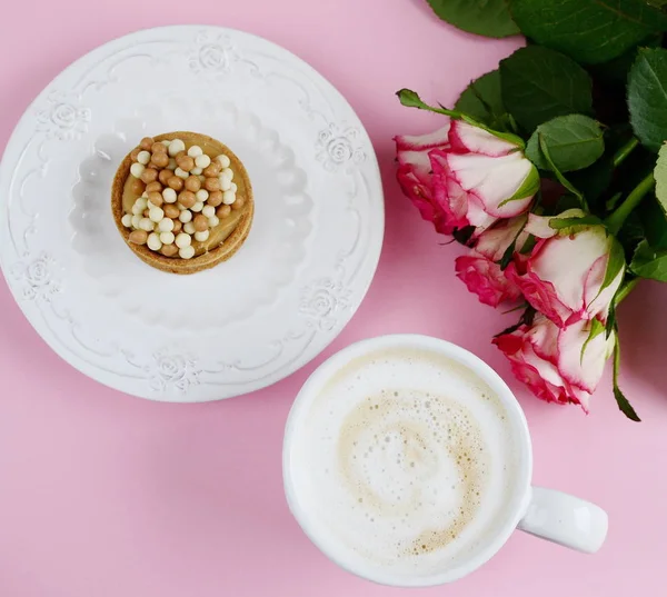 Xícara de cappuccino e bolo com rosas rosa — Fotografia de Stock