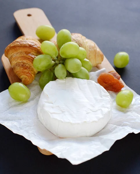 Сыр Бри с круассанами и зеленым виноградом в тарелке — стоковое фото