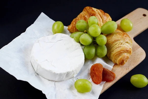 Сыр Бри с круассанами и зеленым виноградом в тарелке — стоковое фото
