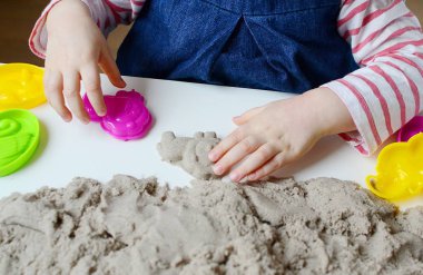 Kinetik kumla oynayan küçük kız