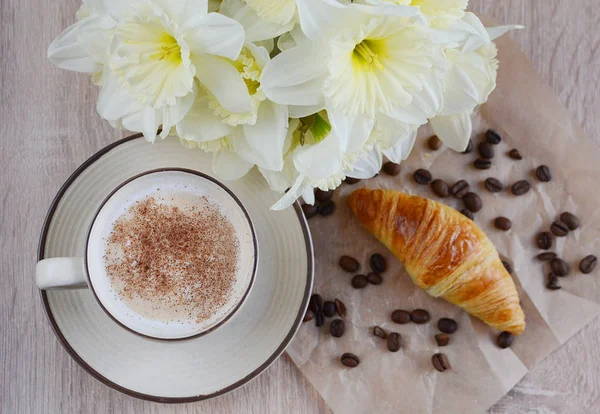 Cup of cappuccino and croissant with flowers