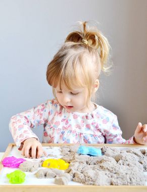 Küçük kız evde Kinetik kumla oynayan 