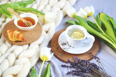 Lavanta çay, narenciye ile fincan ve tatlım, kruvasan, beyaz pastel dev örgü battaniye, yatak odası, çiçek lale, Bahar, kadın gün, sabah kavramı