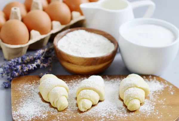 stock image Baking Ingredients for Cooking Croissants. Dough, Eggs, White Sugar, Flour, Milk, Oil Butter. Preparation, Lavender Flowers. Kitchen Cuisine Table Grey Background, Homemade