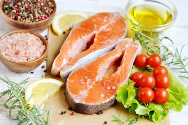 Somon alabalık balık ham fileto yemek biber tuz zeytinyağı biberiye limon yeşil domates salatası ahşap masa yaşam tarzı sağlıklı kavramı