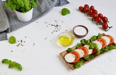 Mozzarella peyniri ile kırmızı domates ve fesleğen yaprağı, biber, zeytin yağı, ahşap Danışma, sağlıklı gıda kavramı, beyaz arka plan