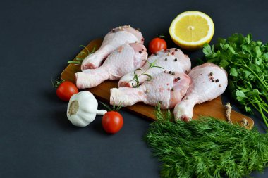 Yeşil otlar ve baharatlar biber ahşap kesme tahtası gıda içerikler tuz biberiye limon yağı hazırlık yaşam tarzı sağlıklı kavramı siyah arka plan üzerinde çiğ tavuk budu