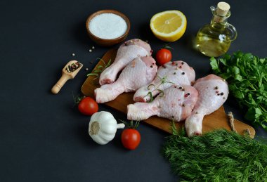 Yeşil otlar ve baharatlar biber ahşap kesme tahtası gıda içerikler tuz biberiye limon yağı hazırlık yaşam tarzı sağlıklı kavramı siyah arka plan üzerinde çiğ tavuk budu