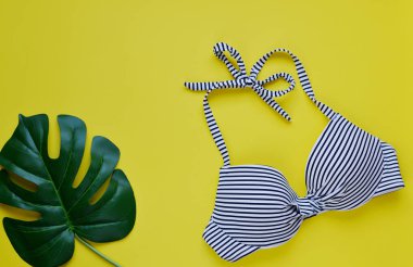 Kadın bikini mayo ve hasır şapka, yaz saati en iyi görünüm düz sarı arka plan kopya alanı afiş kavramı, tropikal yaprak çiçek koymak