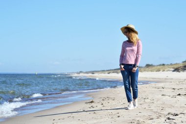 Şapkalı bir genç güzel kadın yürüyor deniz, güneşli bir gün, özgürlük kavramı