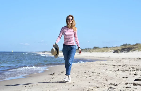 Şapkalı bir genç güzel kadın yürüyor deniz, güneşli bir gün, özgürlük kavramı