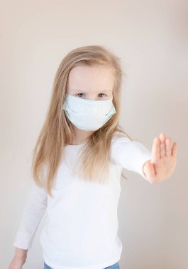 Beyaz bir arka planda yüzünde tıbbi maske olan küçük sarışın kız. Koronavirüs korunuyor.
