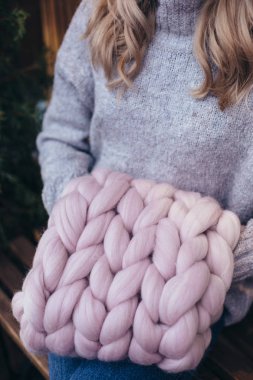 Blonde woman in grey sweater holds smoky pink knitted infinity scarf clipart