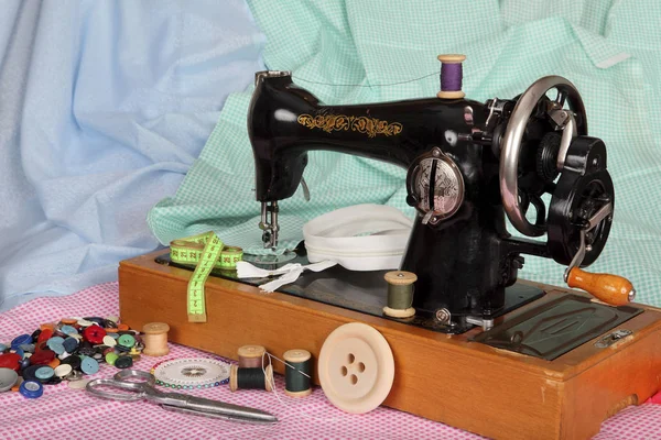 Una vieja máquina de coser a mano con una aguja, bobinas retro con hilos de colores, botones brillantes y piezas de tela de algodón de color — Foto de Stock