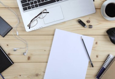 Ofiste masaüstü. Kahve molası ile bir telefon, bir dizüstü bilgisayar, bir bellek kartı, çalışma dizüstü bilgisayarlar ve boş kağıt yığını. Yukarıdan görüntüleyin. Yakın çekim