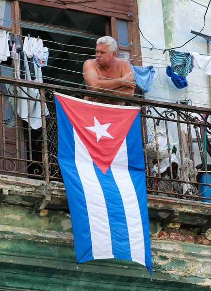 HAVANA, CUBA-JULHO 26,2006: Homem em pé na varanda com a bandeira cubana — Fotografia de Stock