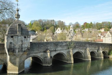 Yemyeşil ağaçlar ve mavi gökyüzü arka plan ile çamurlu nehir üzerinde eski yıpranmış köprü