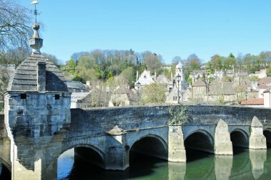 Yemyeşil ağaçlar ve mavi gökyüzü arka plan ile çamurlu nehir üzerinde eski yıpranmış köprü
