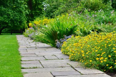 Patika çimen, yeşil ağaçlar ve değişik çiçek