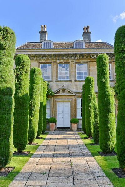 Старый дом с зелеными деревьями и кустами
