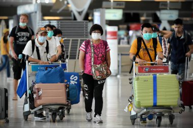 Bangkok, Tayland - 18 Şubat 2020: Maskeli gezginler Suvarnabhumi Havaalanı 'nın kalkış salonundan geçiyor. Tayland, Çin dışında Covid-19 virüsü riski altında..