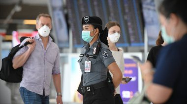 Bangkok, Tayland - 18 Şubat 2020: Maskeli gezginler Suvarnabhumi Havaalanı 'nın kalkış salonundan geçiyor. Tayland, Çin dışında Covid-19 virüsü riski altında..