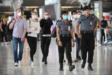 Bangkok, Tayland - 18 Şubat 2020: Maskeli gezginler Suvarnabhumi Havaalanı 'nın kalkış salonundan geçiyor. Tayland, Çin dışında Covid-19 virüsü riski altında..
