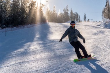 Snowboardcu karlı tepeden aşağı kayıyor