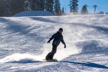 Snowboardcu karlı tepeden aşağı kayıyor