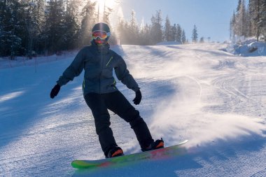 Snowboardcu karlı tepeden aşağı kayıyor
