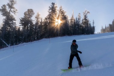 Snowboardcu karlı tepeden aşağı kayıyor