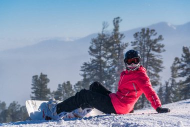 Bir dağ yamacında oturan snowboarder