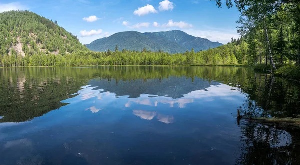 Montagnes et nuages se reflètent dans l'eau du lac chaud — Photo