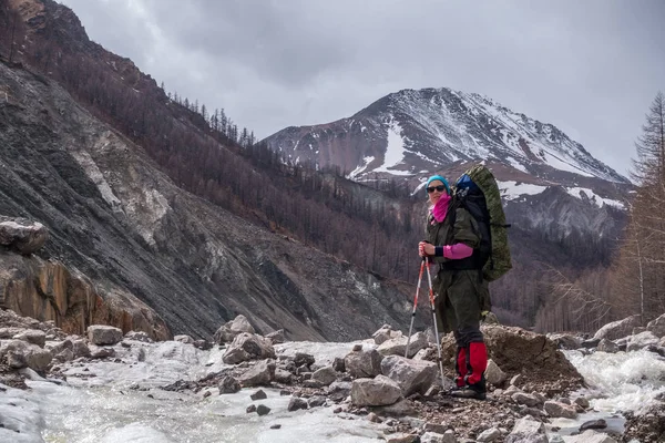 En turist står mitt i en mountain river — Stockfoto