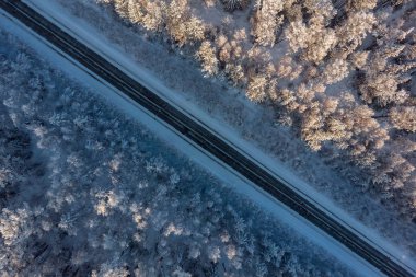Kış ormanının ortasında bir otoyolun havadan görünüşü
