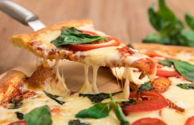 Domates, mozzarella ve fesleğen ahşap zemin, bir dilim peynir germe ile pizza pizza Margherita
