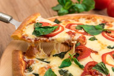 Domates, mozzarella ve fesleğen ahşap zemin, bir dilim peynir germe ile pizza pizza Margherita