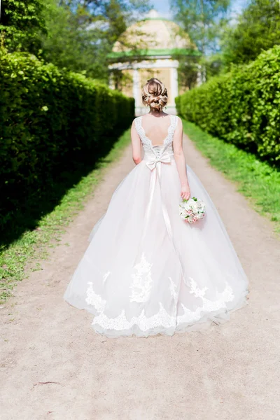 Bruid weglopen in een park holding haar boeket Stockfoto