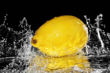 taze limon suyu düşüyor. siyah arka plan üzerine izole