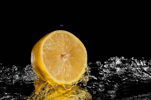 Limón fresco cayendo al agua. Aislado sobre fondo negro — Foto de Stock