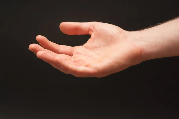 Brazo derecho masculino pidiendo una posición de limosna sobre fondo negro aislado ancho abstracto . — Foto de Stock