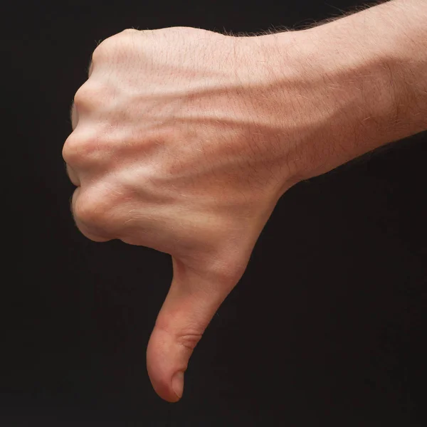 Right male arm demonstrating dislike symbol in front of wide abstract seamless black background. — Stock Photo, Image