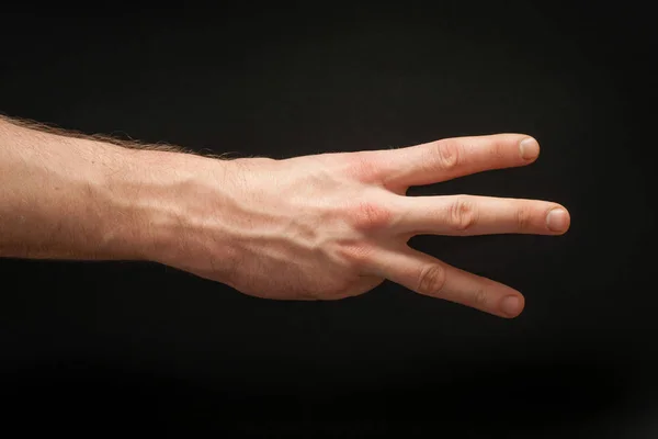 Права чоловіча рука, що показує позицію відліку три ізольовані на широкому абстрактному безшовному чорному тлі . — стокове фото