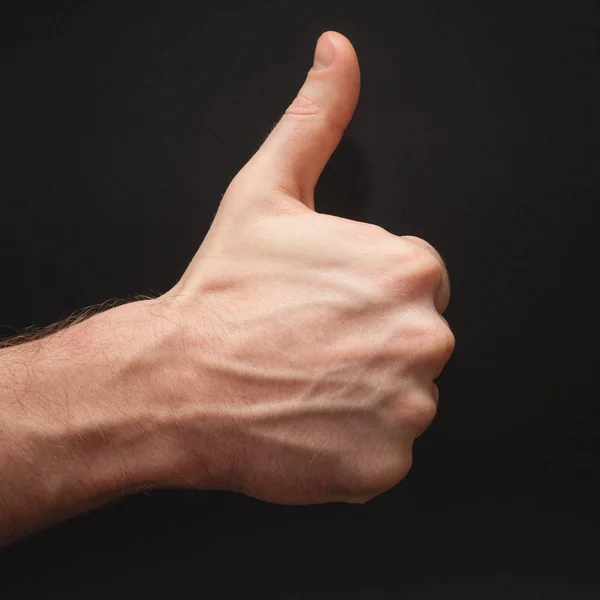 Права чоловіча рука, що демонструє як символ перед широким абстрактним безшовним чорним тлом Стокова Картинка