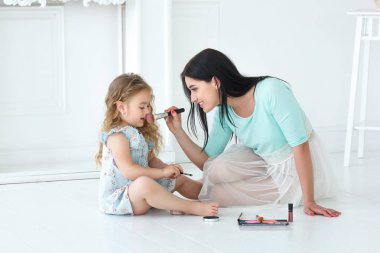 Küçük kızı ve annesi ışık odasında makyaj uygulamak