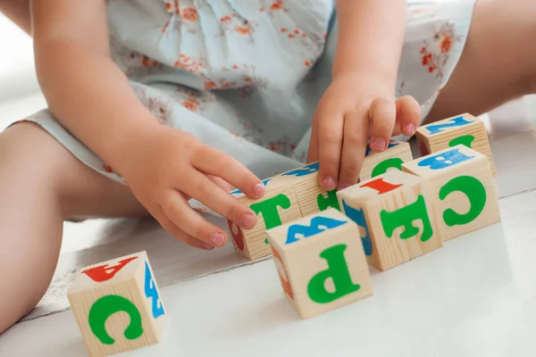 Irreconhecível pouco bonito menina jogar com abc cubos e educa — Fotografia de Stock